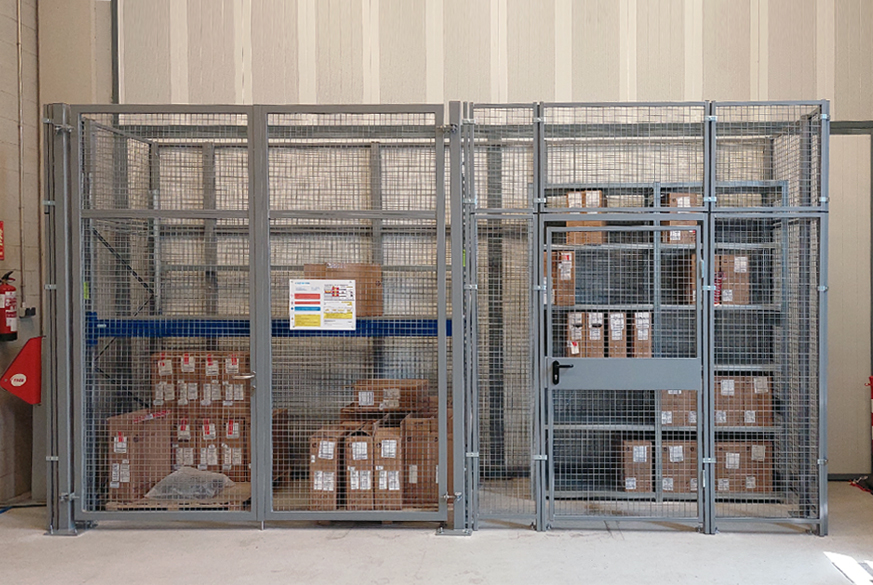 Protección de material depositado en estanterías mediante un cerramiento metálico de malla con puertas de acceso, una peatonal y otra para acceder con apilador y dos estanterías interiores, una de picking y otra de paletización. Instalada en almacén de recambios de empresa de transportes.